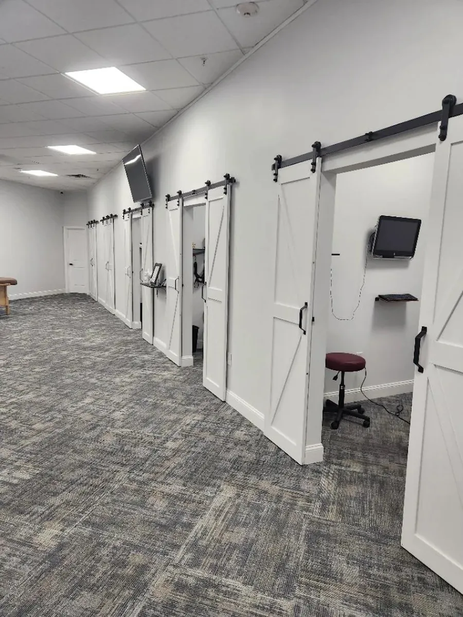A corridor of private treatment bays behind white barn doors.