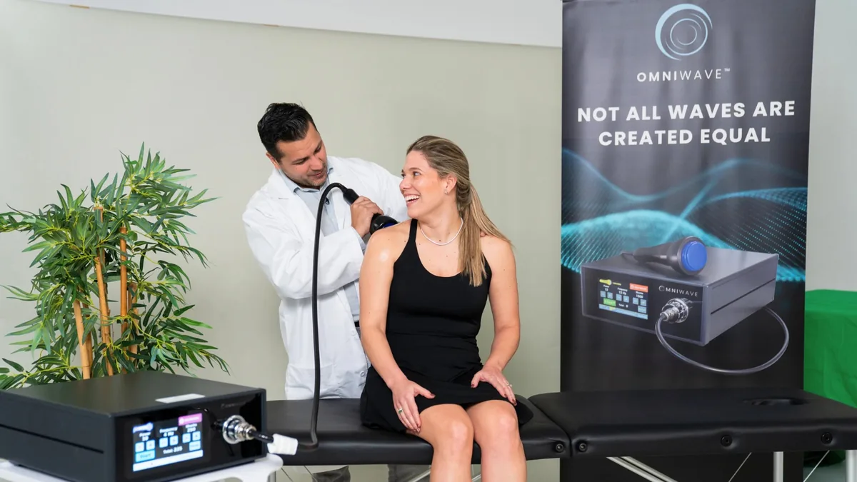 Omniwave shockwave therapy being applied to a seated patient.