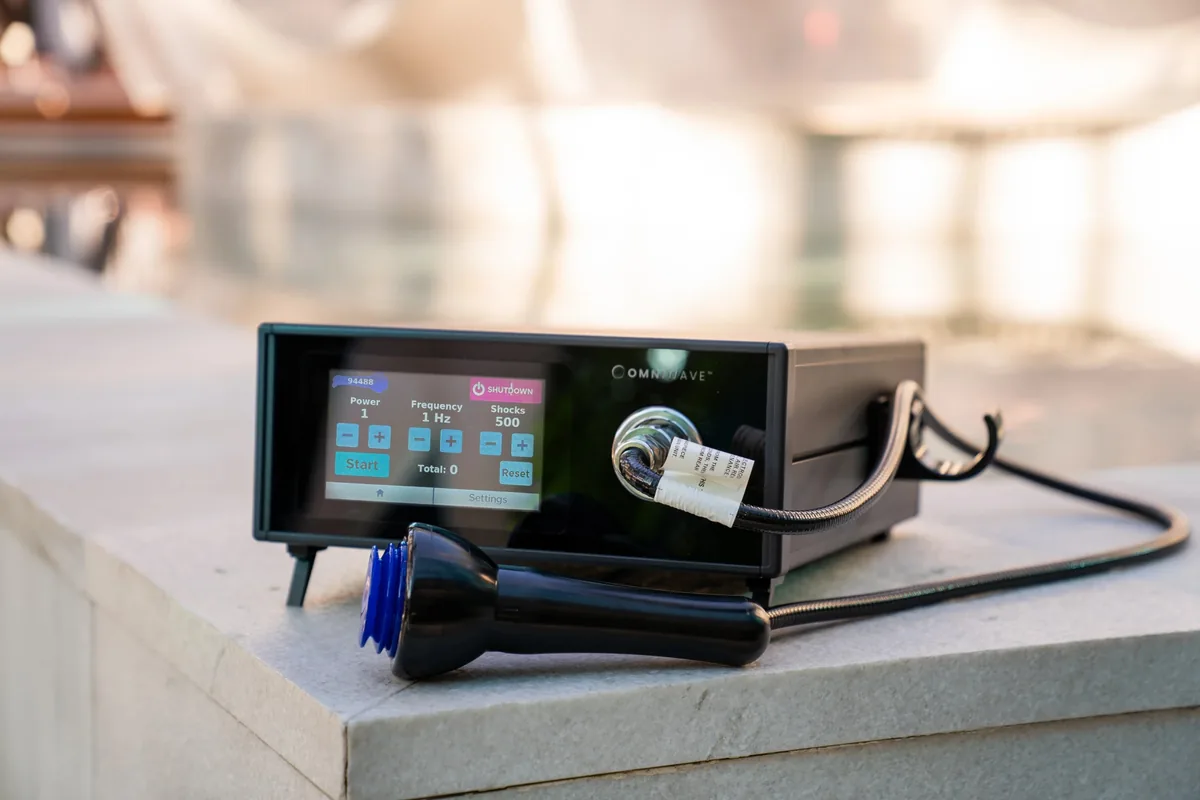 The Omniwave shockwave console and applicator, its screen showing the session settings.